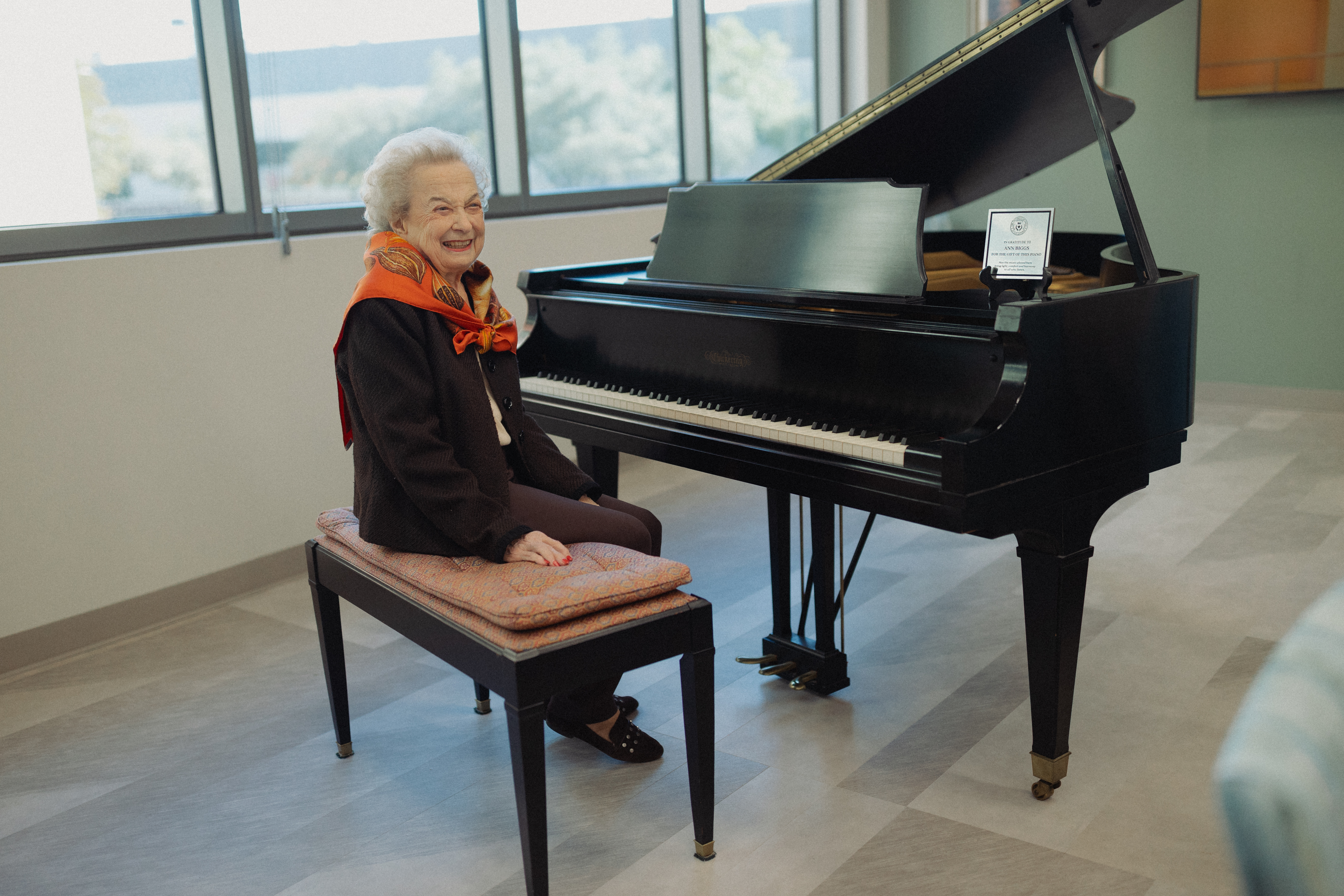 Ann Biggs sitting next to her now donated piano, located at the UT Health San Antonio Center for Brain Health.