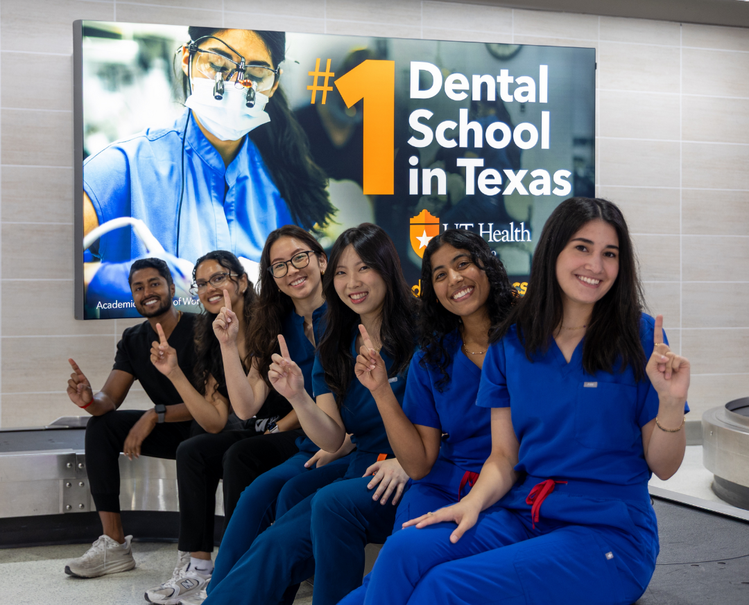 Hamsi Nathan and colleagues posing in front of a School of Dentistry promotional sign.