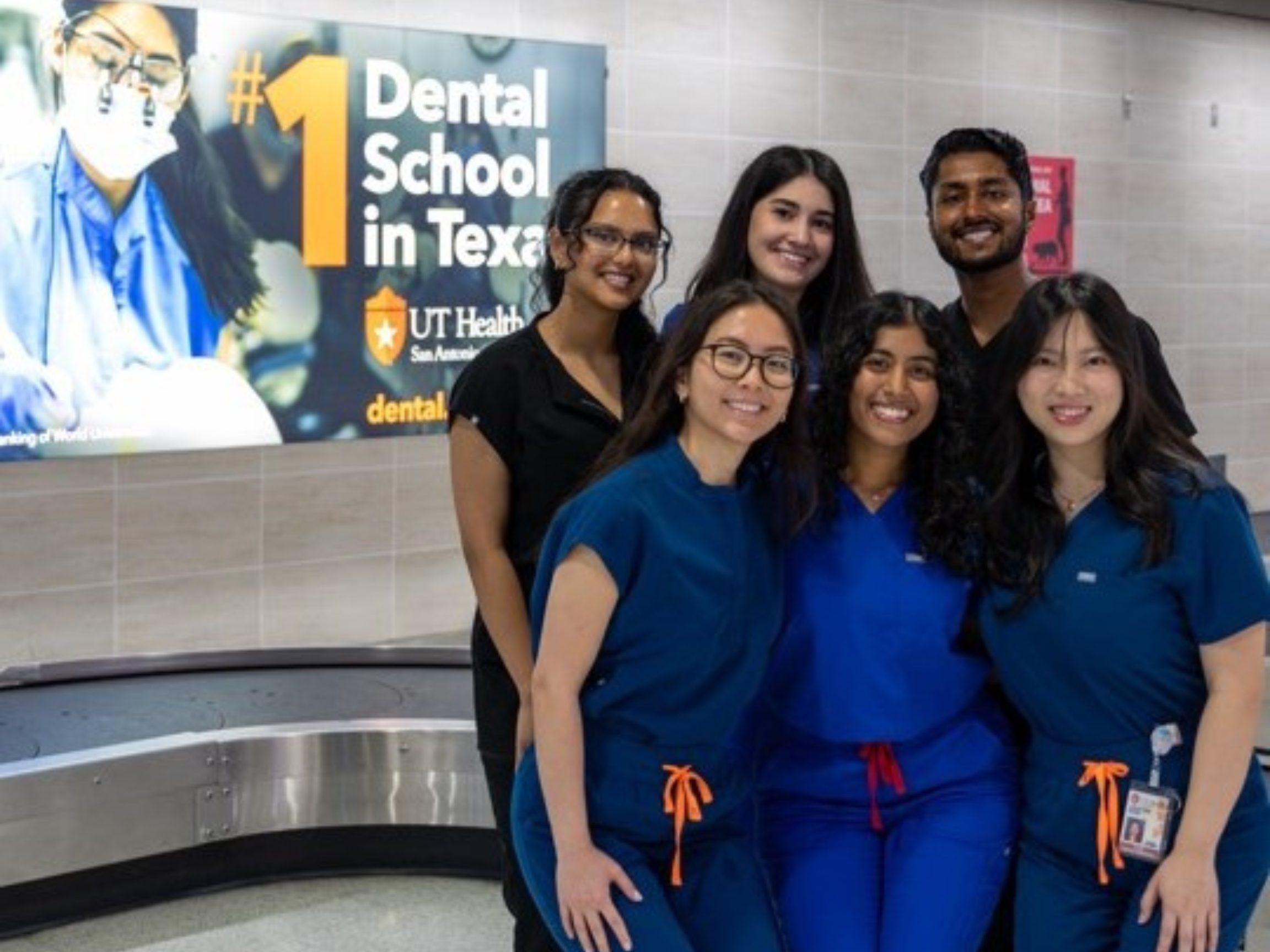 Hamsi Nathan and colleagues posing in front of a School of Dentistry promotional sign.