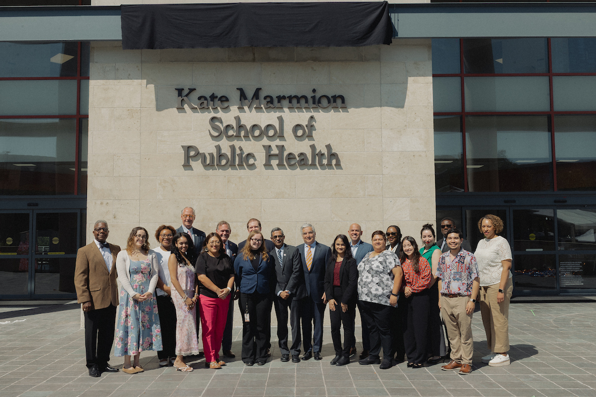 Students and leaders stand below new Kate Marmion School of Public Health sign