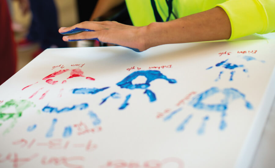 Patients placing painted handprint on canvas during ceremony