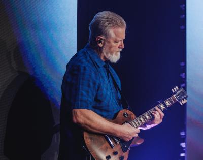 Photo of Brian Smothers playing guitar on stage at his local church.