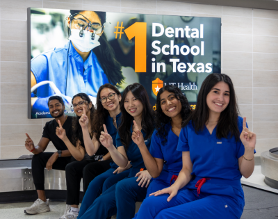 Hamsi Nathan and colleagues posing in front of a School of Dentistry promotional sign.