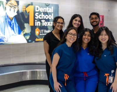 Hamsi Nathan and colleagues posing in front of a School of Dentistry promotional sign.
