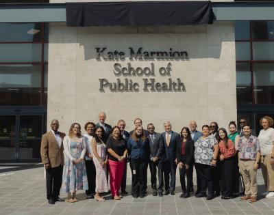 Students and leaders stand below new Kate Marmion School of Public Health sign
