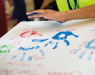 Patients placing painted handprint on canvas during ceremony